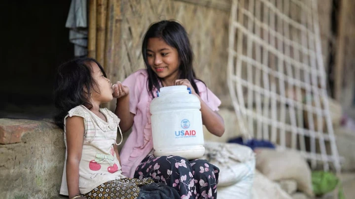 A Rohingya girl feeds a child from a jar with the USAID logo on it, at a refugee camp in Cox's Bazar, Bangladesh, February 11, 2025. Photo: REUTERS/Ro Yassin Abdumonab/File Photo